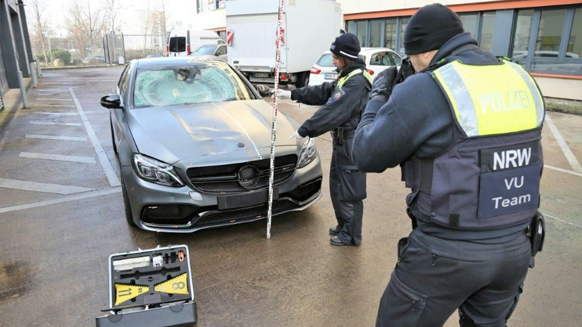 Ein Mercedes wird von einem Kölner Polizisten und einer Polizistin fotografiert.
