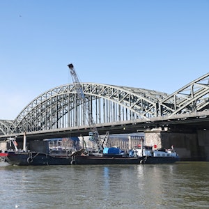Die Hohenzollernbrücke soll verbreitert werden. Zwei Arbeitsschiffe liegen an einem der Pfeiler.