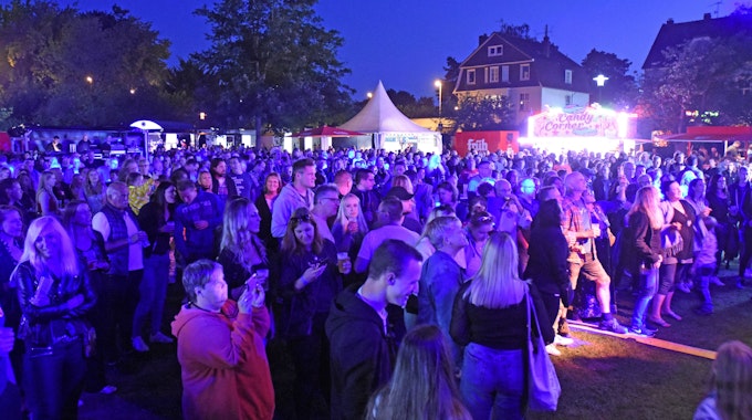 Publikum bei abendlicher Beleuchtung vor der Bühne im Stadtpark