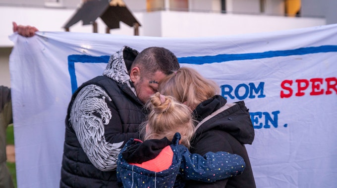 Protestkundgebung gegen Zwangsräumung von sechsköpfiger Familie in Gremberghoven: Vater, Mutter und ein Kind umarmen sich.