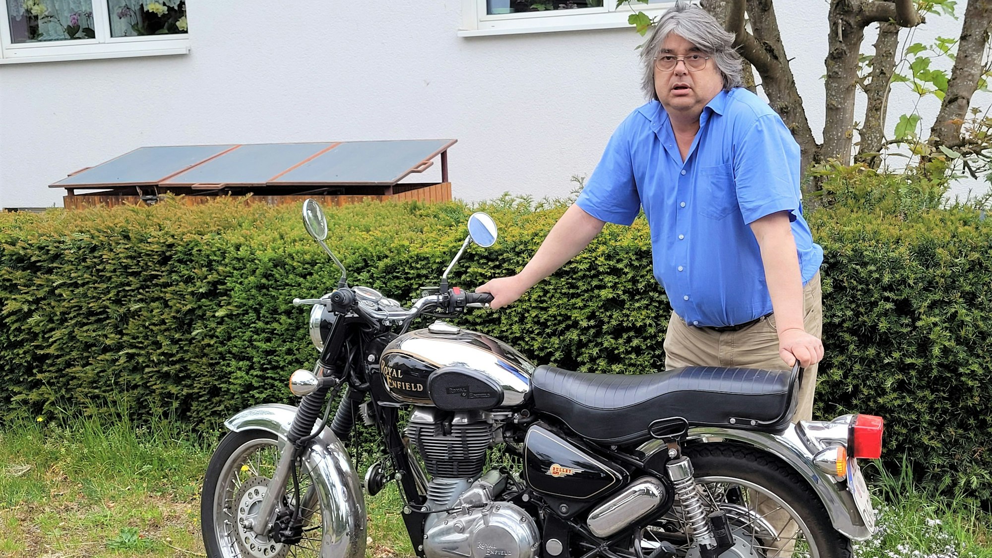 Ein Mann steht an einem Motorrad.