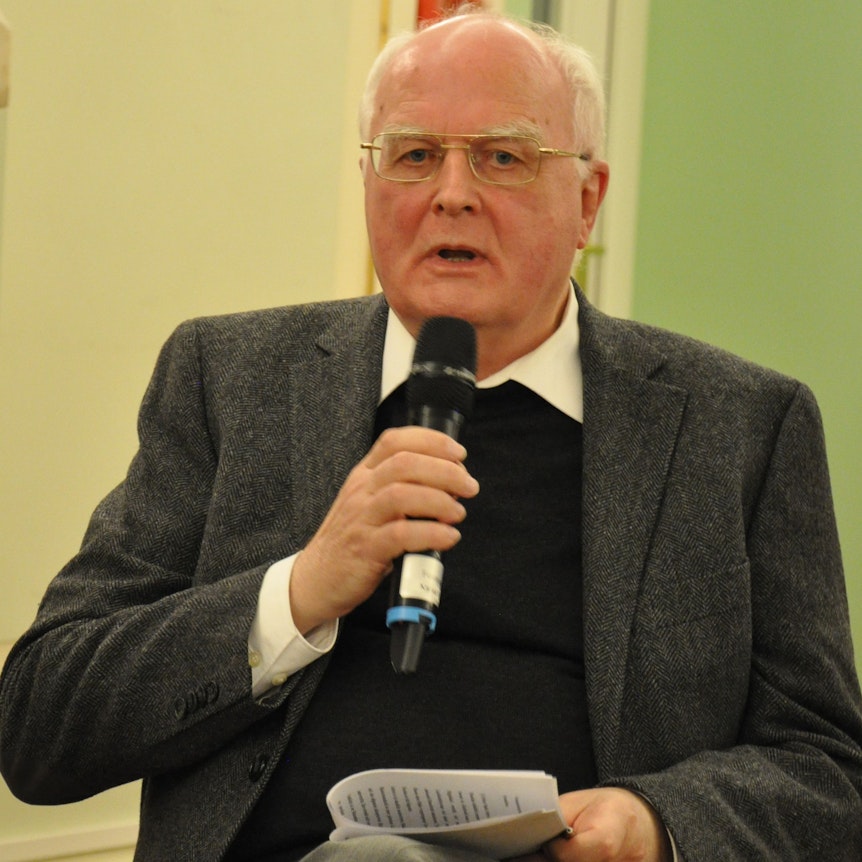 Der emeritierte Bonner Dogmatik-Professor Karl-Heinz Menke diskutiert im Festsaal der Universität Bonn. Er hält ein Mikrofon n der rechten und ein Manuskript in der linken Hand.