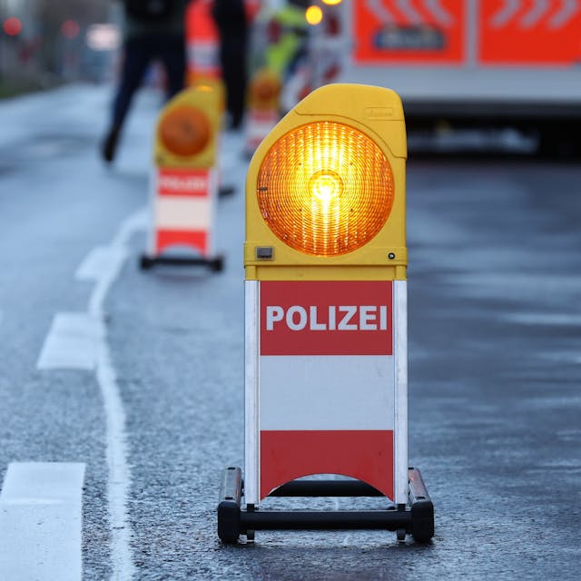 Eine Warnbarke mit der Aufschrift „Polizei“ steht vor einem Rettungswagen an einer abgesperrten Unfallstelle. (Symbolbild)
