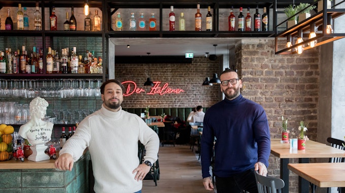 Nermin Music (links) und Marco Baron stehen in ihrem Restaurant, im Hintergrund sieht man an der Backsteinwand einen Neon-LED-Schriftzug mit "Der Italiener".