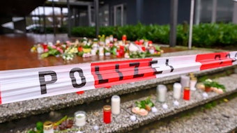 Auf einer Treppe vor dem Berufskolleg Tecklenburger Land wurden Kerzen und Blumen abgelegt. Ein Absperrband der Polizei spannt über den Stufen.
