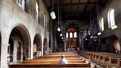 Eine Frau sitzt alleine in der Kirche St. Laurentius in Bergisch Gladbach.