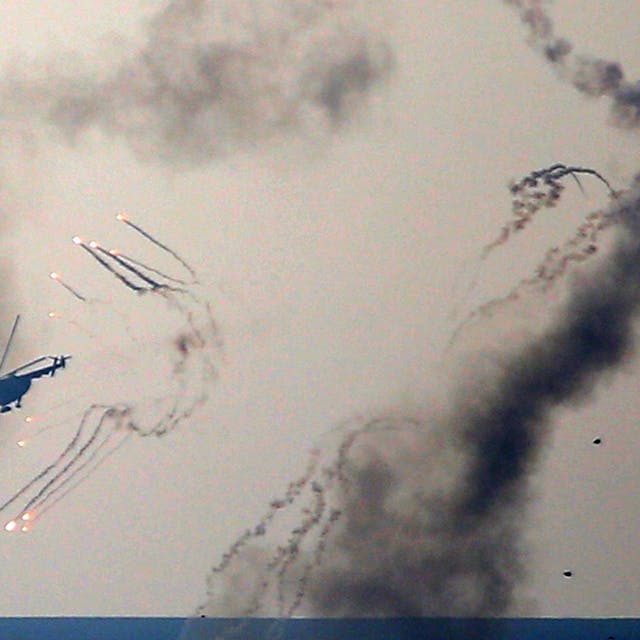 Ein ukrainischer Helikopter feuert Abwehrgeschütze ab und Rauch steigt auf.