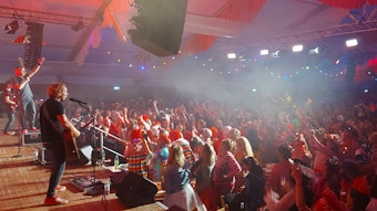 Eine Band steht auf der Bühne, die Fans in Karnevalskostümen feiern in einem Festzelt.