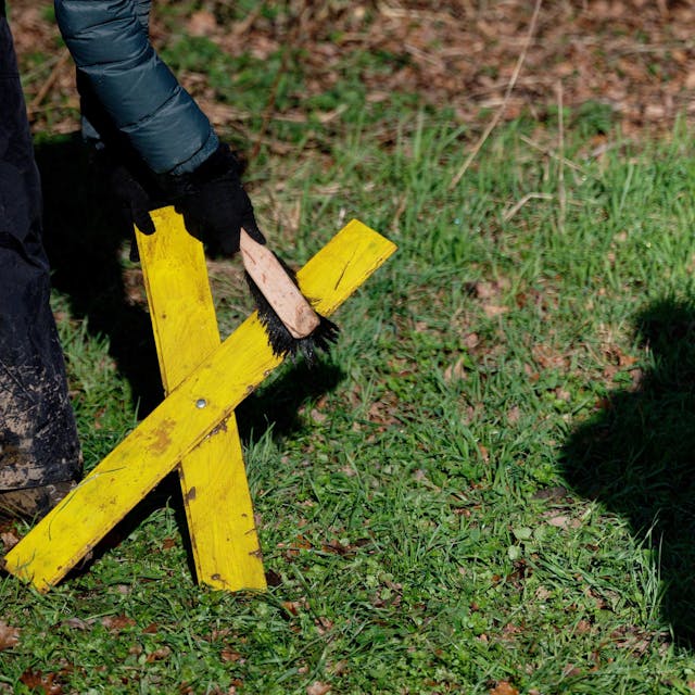 Eine Aktivistin reinigt in Lützerath in Keyenberg ein Gelbes Kreuz.