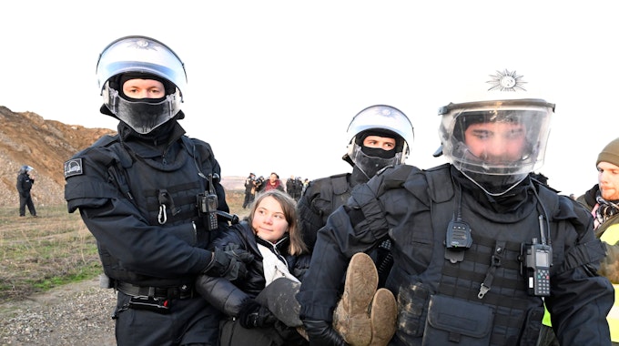 Polizisten tragen die schwedische Klimaaktivistin Greta Thunberg (M) aus einer Gruppe von Demonstranten und Aktivisten heraus und vom Rand des Braunkohlentagebaus Garzweiler II weg.