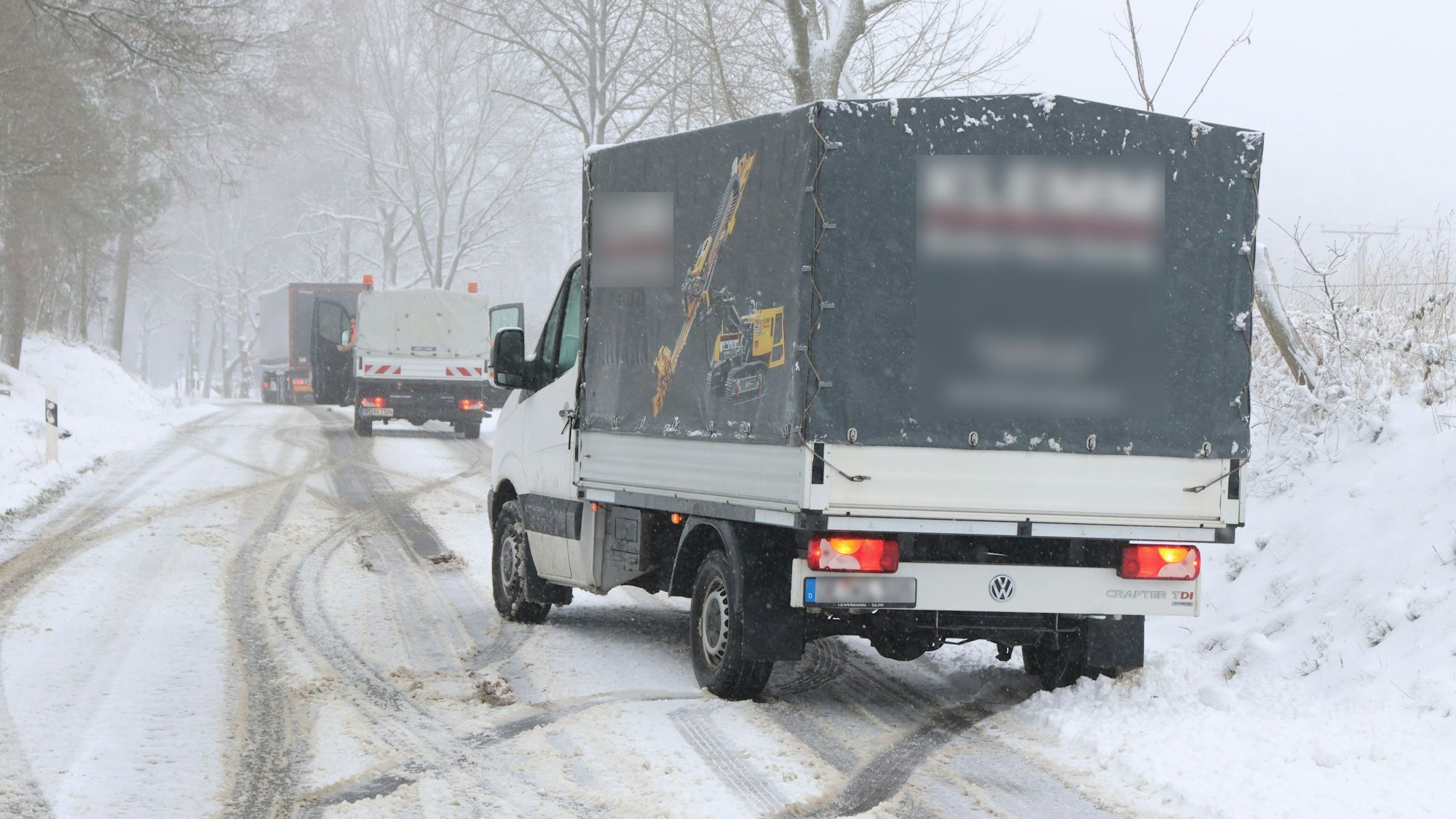 Mehrere Kleintransporter und Lkw sind von einer mit Schnee bedeckten Straße abgekommen und steckt am Rand fest