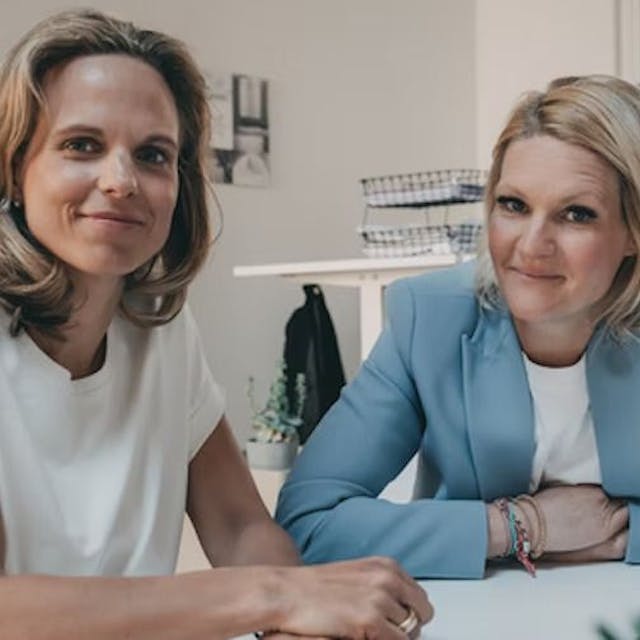 Die beiden Gründerinnen von Badesofa Natalie Steger (links) und Annika Götz sitzen an einem Besprechungstisch.
