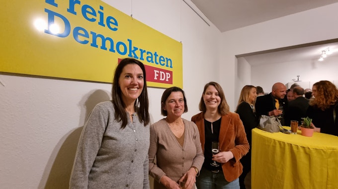 Drei Frauen stehen mit einem Glas Sekt in der Hand vor einem Banner mit der Aufschrift "Freie Demokraten - FDP" und lächeln in die Kamera.