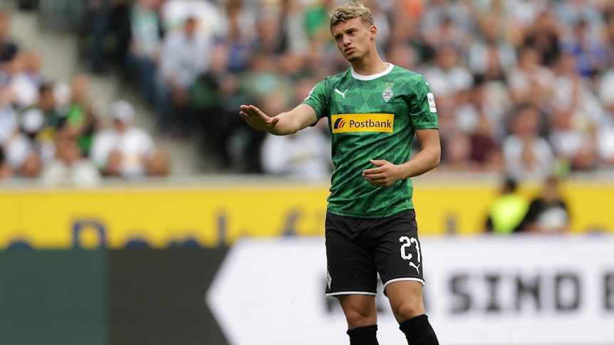 Michael Cuisance im Trikot von Borussia Mönchengladbach am 3. August 2019. Der Mittelfeldspieler aus Frankreich trägt ein grünes Gladbach-Trikot und macht eine beruhigende Geste mit seinem rechten Arm.