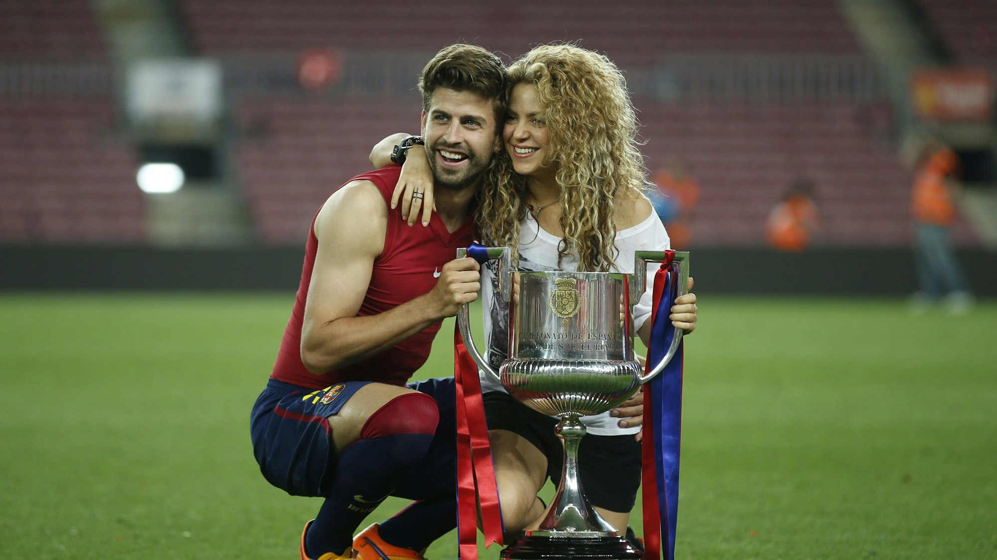 Gerard Pique posiert mit seiner Frau Shakira vor einem Pokal.