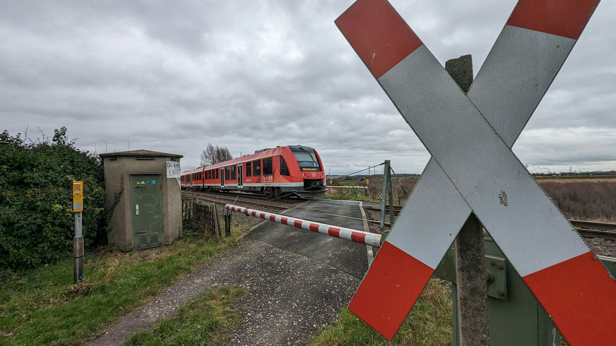 Am Bahnübergang „Am Kirchtürmchen“ fährt ein Zug vorbei. Im Vordergrund steht ein Andreaskreuz.