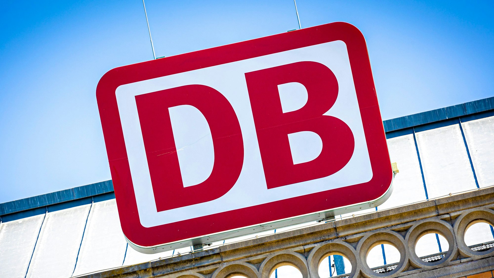 Das Logo der Deutschen Bahn über einem Hauptbahnhof.
