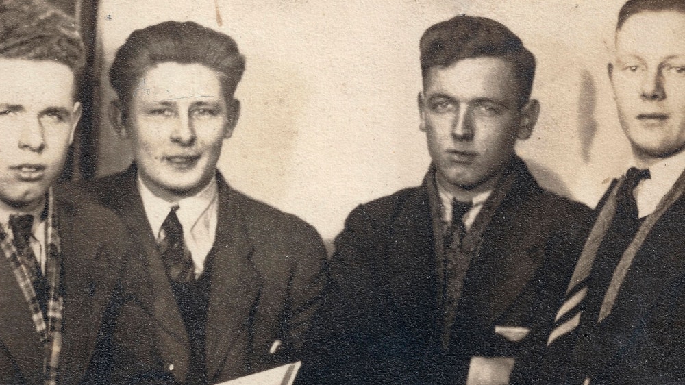 Auf einem alten Schwarz-Weiß-Foto stehen vier junge Männer in Anzug nebeneinander.