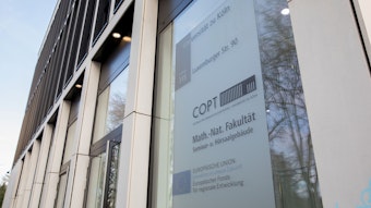 Das Bild zeigt die Außenansicht des COPT-Zentrums der Uni Köln mit einem Schild.
