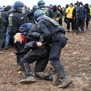 Zwei Polizisten ziehen einen Demonstranten während der Proteste gegen den Abriss von Lützerath weg.