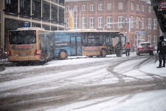 Am Bahnhof Euskirchen steht ein Gelenkbus quer auf der Straße. Es liegt und fällt Schnee.
