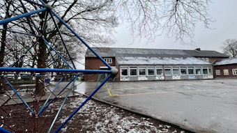 Blick über einen Schulhof auf ein Schulgebäude