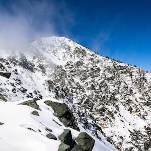 Mount San Antonio, auch Mount Baldy genannt, ist mit Schnee bedeckt. Über dem Gipfel hängt Nebel, es ist eine kleine Fußspur zu sehen.