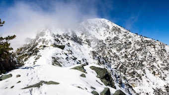 Mount San Antonio, auch Mount Baldy genannt, ist mit Schnee bedeckt. Über dem Gipfel hängt Nebel, es ist eine kleine Fußspur zu sehen.