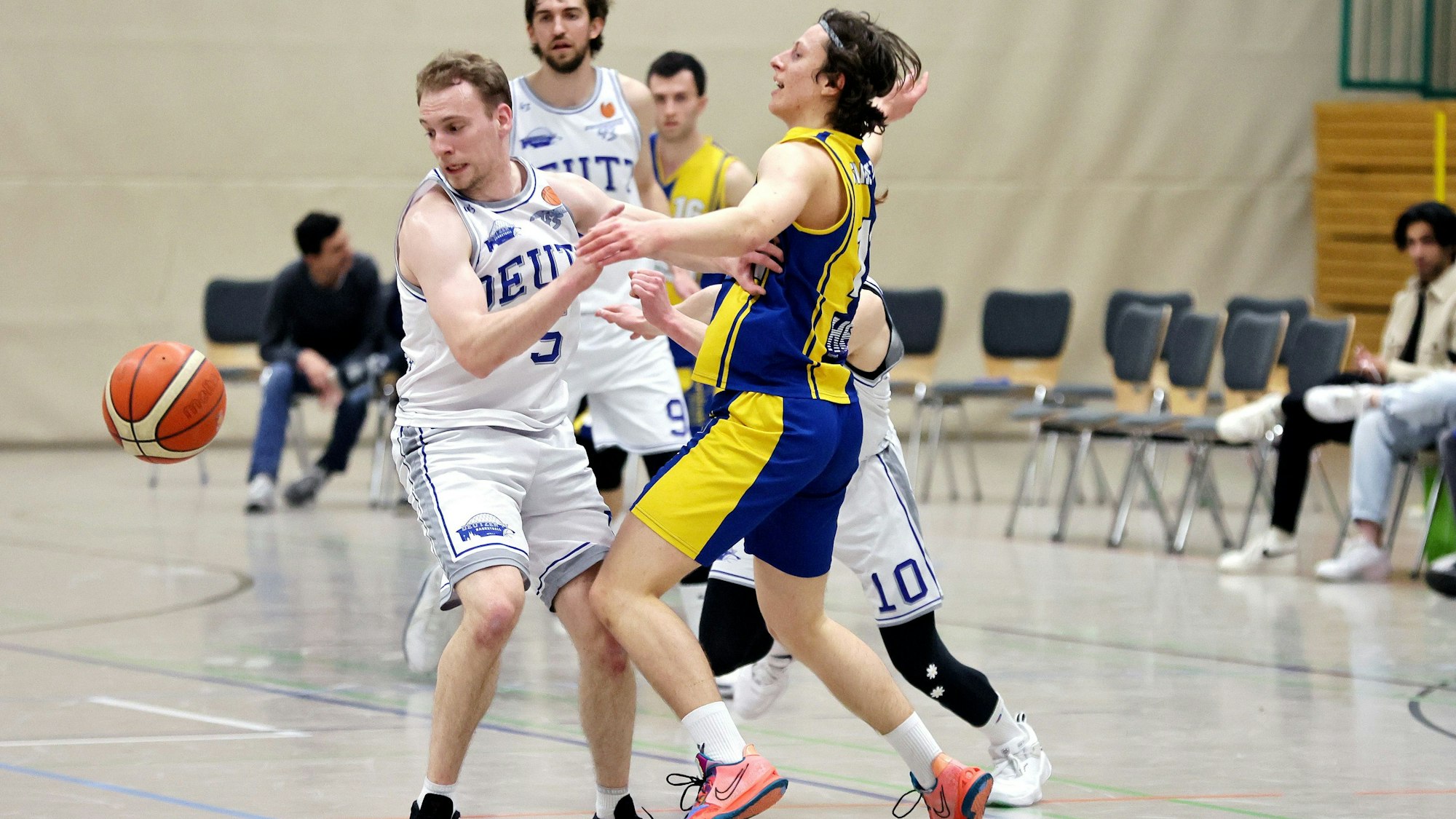 Ein Basketballspieler wird von seinem Gegner gestoppt.