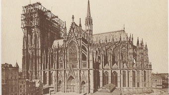 Das historische Foto vom Weiterbau des Kölner Doms zeigt den Zustand im Mai 1876 mit den noch unvollendeten Türmen. Im Vordergrund sieht man die Dombauhütte.