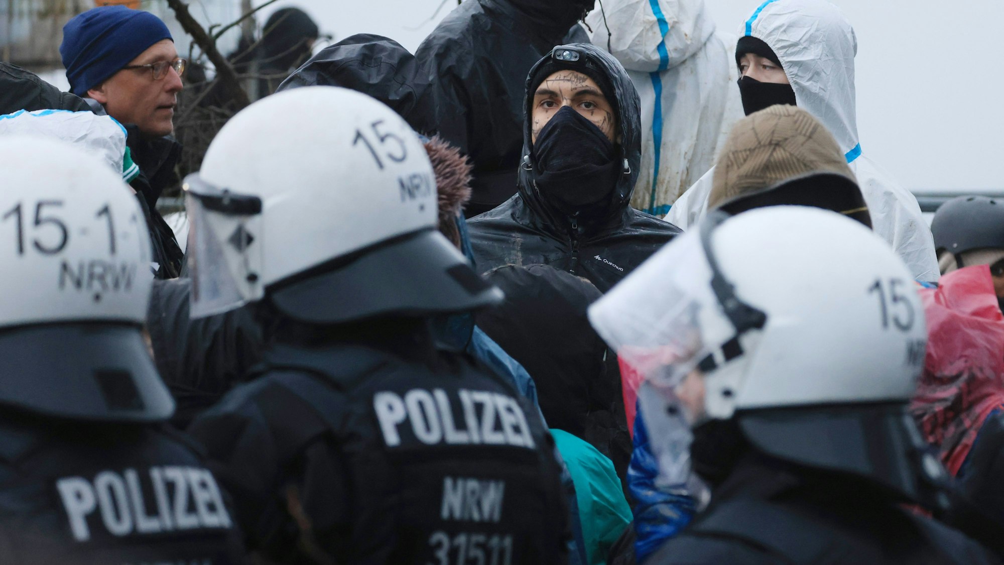 Aktivisten und Polizisten stehen sich am Rande des besetzten Braunkohleorts Lützerath direkt gegenüber.