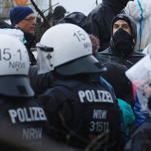 Aktivisten und Polizisten stehen sich am Rande des besetzten Braunkohleorts Lützerath direkt gegenüber.