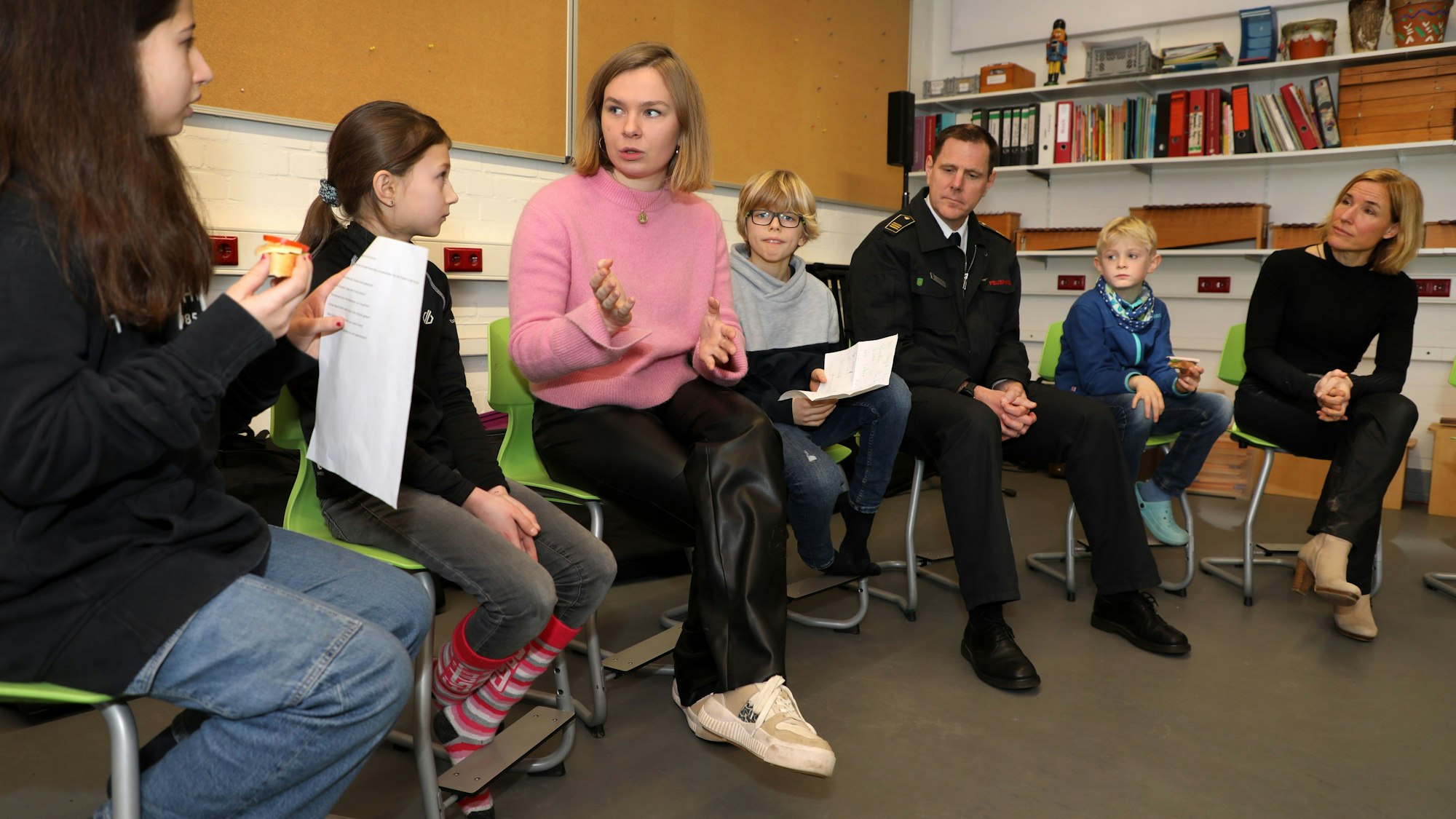 Alina Saraniuk erzählt mit Schülern in einem Stuhlkreis, in dem auch Feuerwehrchef Jörg Köhler und Schulleiterin Sonja Frohleiks sitzen.