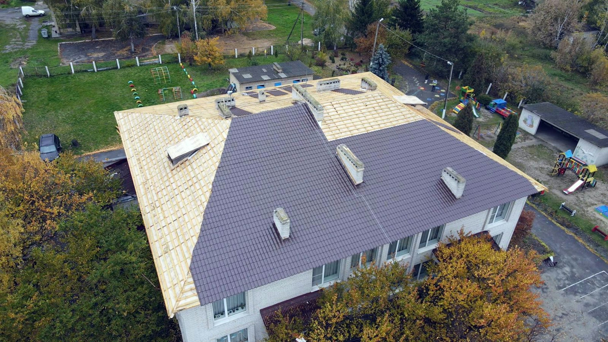 Ein neues Dach auf einem Gebäude wird fertiggestellt. Noch fehlt die Hälfte der Dachziegel.