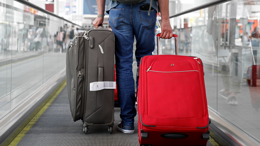 Ein Mann läuft über den Flughafen in Palma de Mallorca und zieht zwei Koffer hinter sich her.