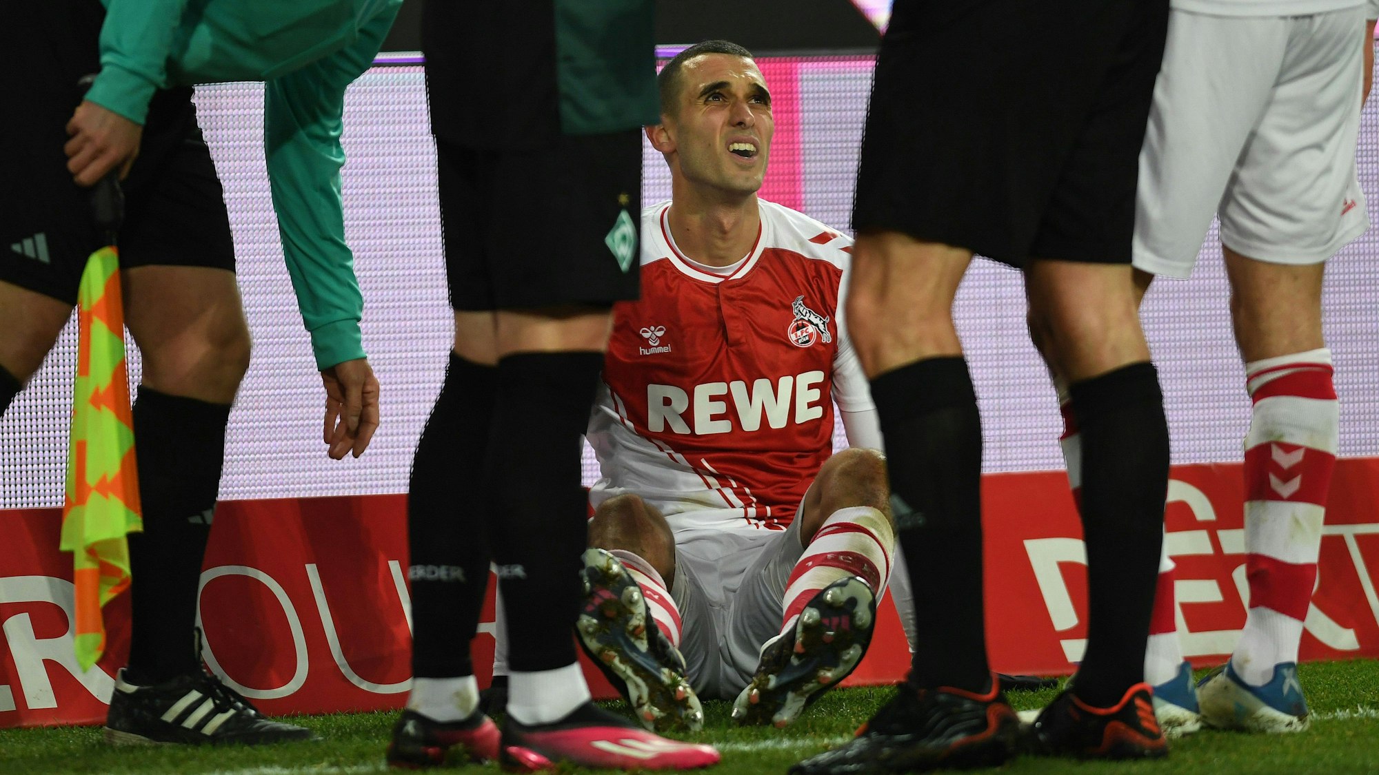 Ellyes Skhiri sitzt beim 1. FC Köln verletzt auf dem Rasen.