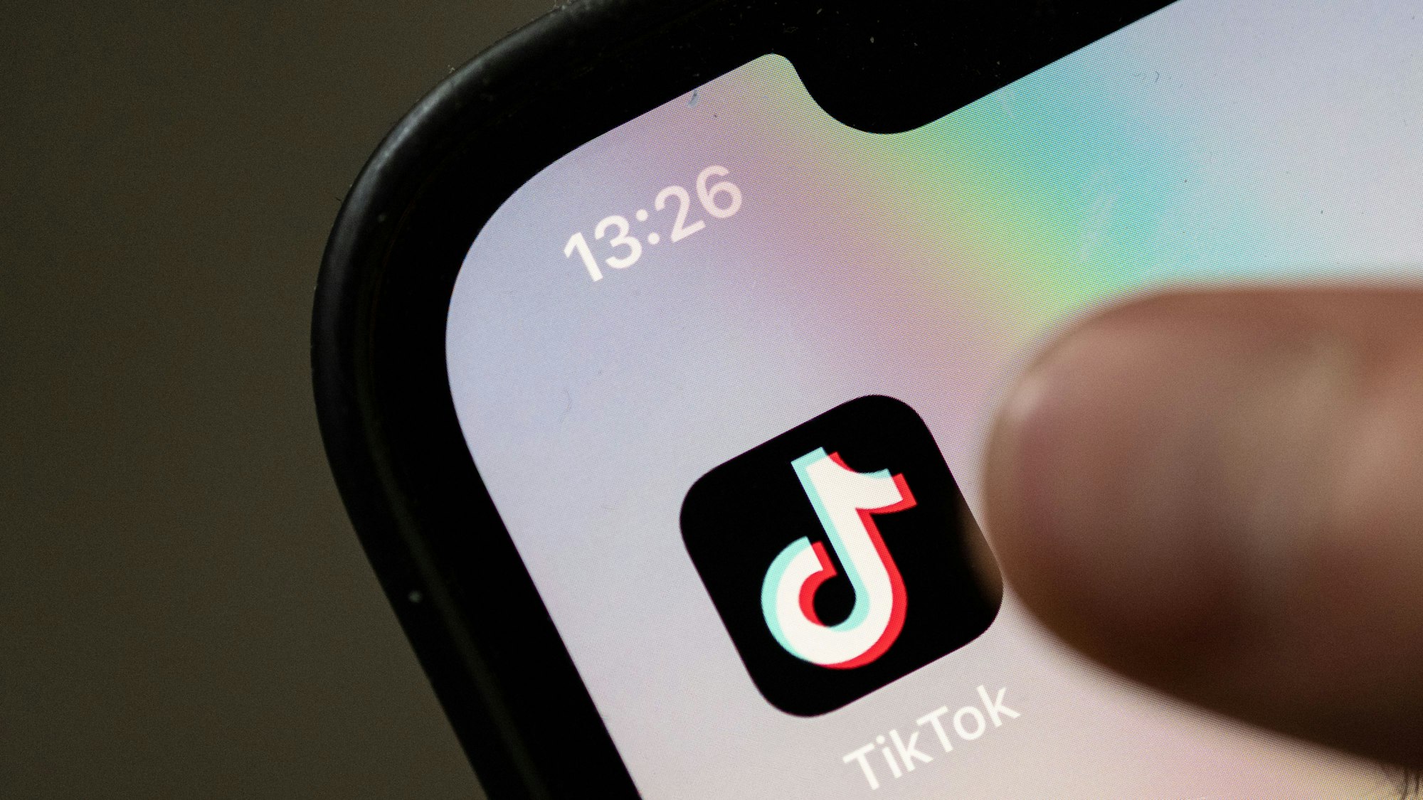 Ein Teenager tippt auf das Icon TikTok-App auf einem Smartphone.