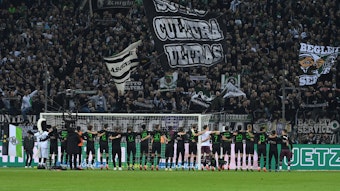 Die Spieler von Borussia Mönchengladbach stehen Arm in Arm vor der Nordkurve im Borussia-Park und feiern den Bundesliga-Sieg gegen Borussia Dortmund am 11. November 2022 mit den Fans auf der Stehplatz-Tribüne.