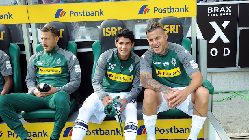 Raul Bobadilla (r.) sitzt am 9. September 2017 auf der Bank im Borussia-Park neben Julio Villalba und lächelt in die Kamera. Links ist Fabian Johnson zu sehen.