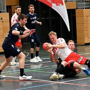 Ein Handballer wird von seinem Gegenspieler auf den Boden gezogen.