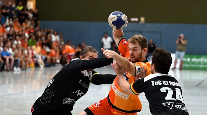 Ein Handballspieler setzt sich gegen zwei Gegner durch.