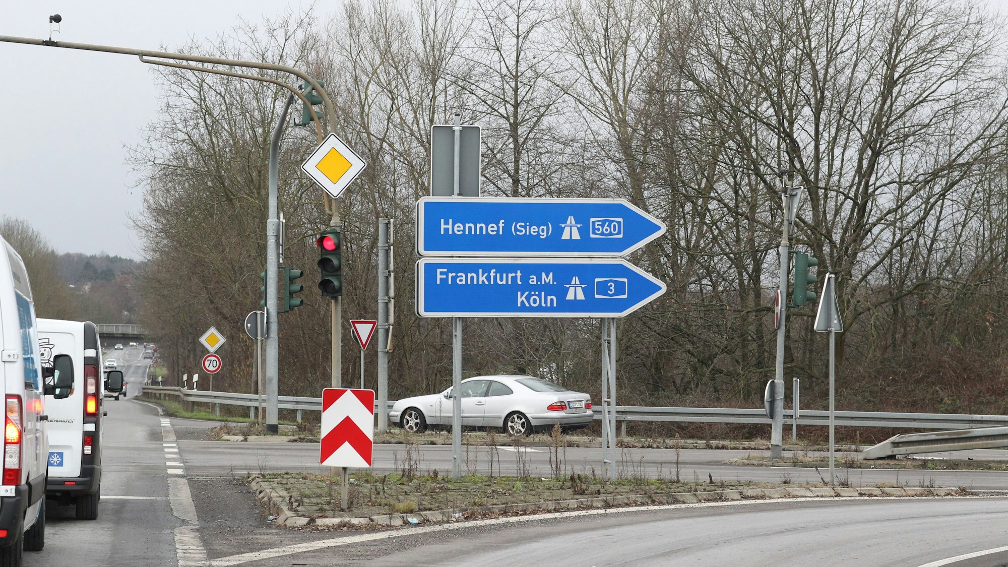 An einer Ampel mit einem Rechtsabbieger stehen zwei Schilder, die auf die A 560 zeigen. Eines weist die Richtungen Frankfurt und Köln der A3 aus.