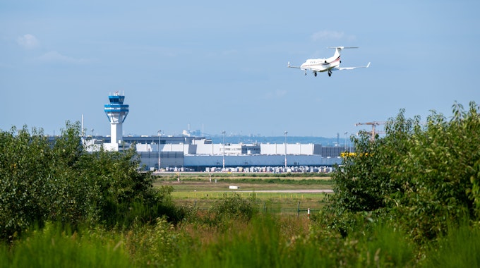 Ein Flugzeug landet auf dem Flughafen Köln/Bonn. Das Rollfeld ist aus der Ferne zu sehen.
