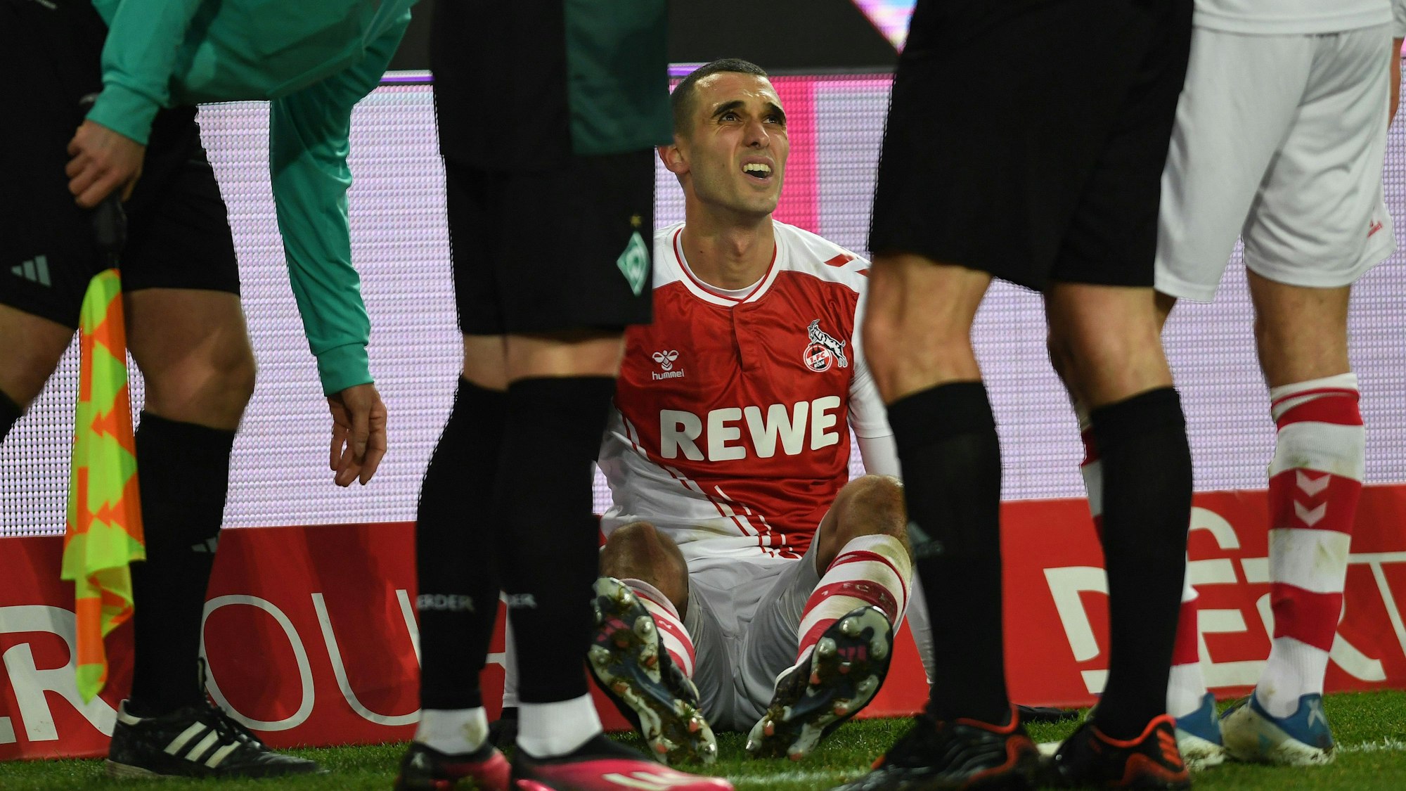 Der Kölner Mittelfeldspieler Ellyes Skhiri sitzt am Boden, nachdem er sich am Sprunggelenk verletzt hat.