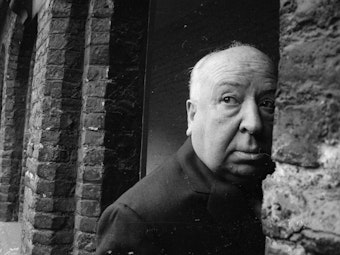 Alfred Hitchcock schaut an einer Wand vorbei.