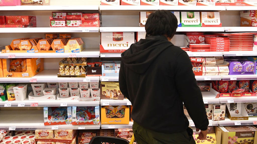 Ein Mann steht vor dem Schokoladenregal in einem Supermarkt.