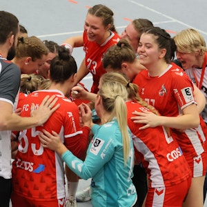 Ein Frauen-Handballteam steht im Kreis zusammen und freut sich über einen Sieg.