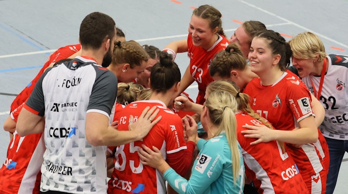 Ein Frauen-Handballteam steht im Kreis zusammen und freut sich über einen Sieg.