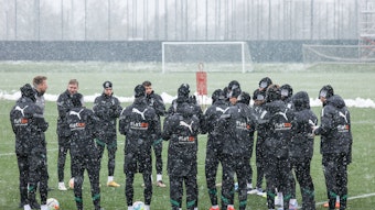 Bei dichtem Schneefall versammelt sich die Mannschaft von Borussia Mönchengladbach am 20. Januar 2023 in einem Kreis bei einer Trainingseinheit. Aufgenommen wurde das Foto auf dem Trainingsplatz im Borussia-Park.
