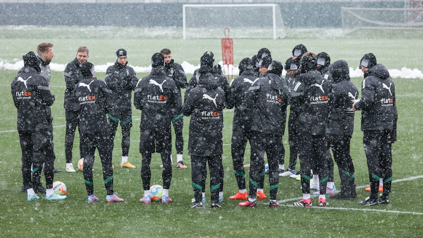 Bei dichtem Schneefall versammelt sich die Mannschaft von Borussia Mönchengladbach am 20. Januar 2023 in einem Kreis bei einer Trainingseinheit. Aufgenommen wurde das Foto auf dem Trainingsplatz im Borussia-Park.